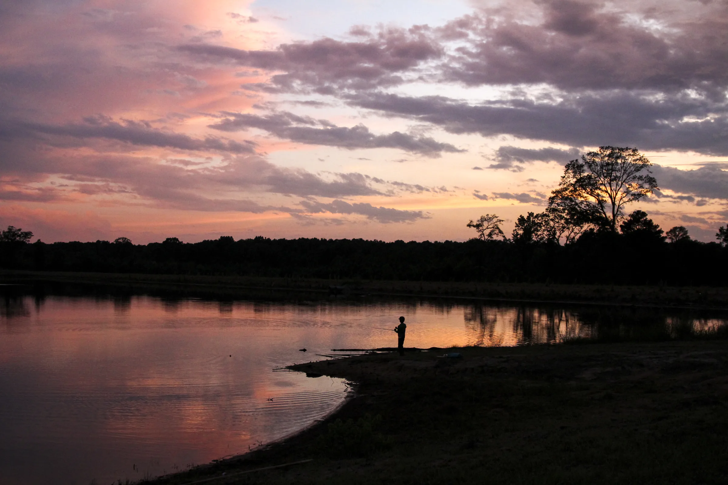 A camper fishing at sunset on Lake Huawni