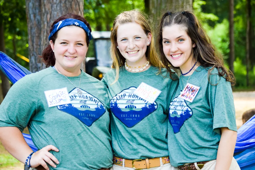 Three Camp Huawni counselors in staff shirts with handwritten name tags